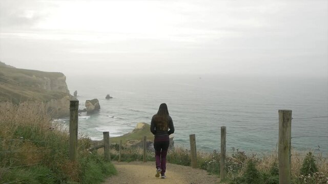 Woman walking Beautiful Coastline Trail in Dunedin New Zealand