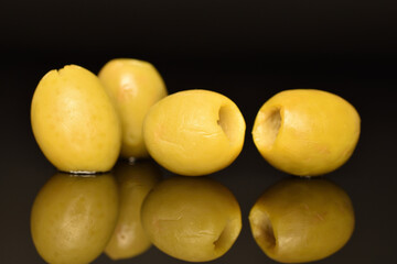Green pitted olives, close-up, on a black background.