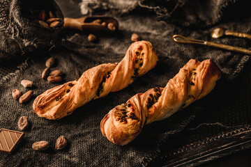 Freshly backed twisted cakes or puff pastry buns with chocolate on rustic sackcloth background....