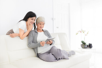 young Asian female and old female search information with tablet computer, they feeling happy and...