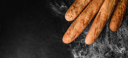 Freshly bread baguettes on black slate background with flour. Pastries and bakery, Food concept,...