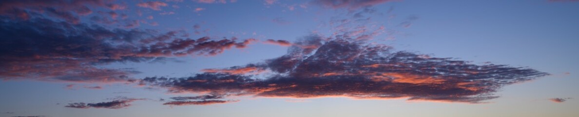 beautiful panoramic photo of the blue sky and clouds painted pink by the sunset