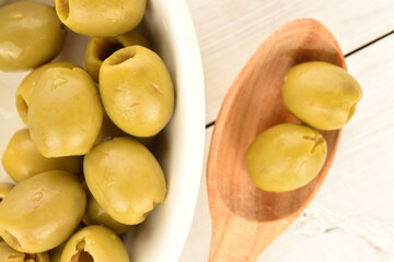 Tinned green pitted olives, close-up, on a wooden table.