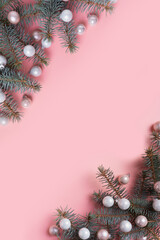 Christmas white balls and fir branches on pink. Xmas vertical banner with space for text. View from above.