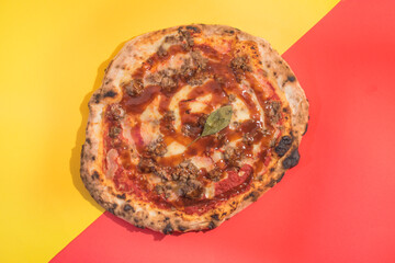Pizza with meat and barbecue sauce with red and yellow color background