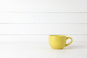 Fototapeta na wymiar Yellow coffee mugs on white wood background with copy space.