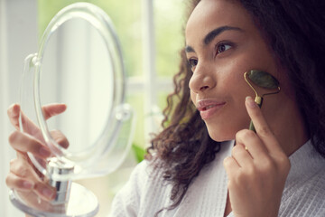 Young woman using jade roller at home © Yakobchuk Olena