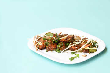 Chilli paneer or Spicy cottage cheese, Garnish with capsicum, onion,cabbage and spring onion, favourite indian starter menu, served in white Dish,selective focus
