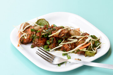 Chilli paneer or Spicy cottage cheese, Garnish with capsicum, onion,cabbage and spring onion, favourite indian starter menu, served in white Dish,selective focus