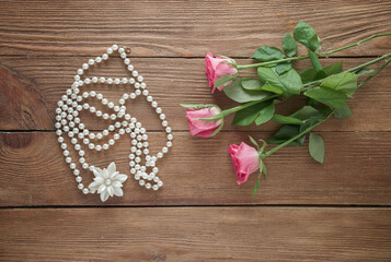 Obraz na płótnie Canvas Women's accessories and pink roses on a wooden background, top view.