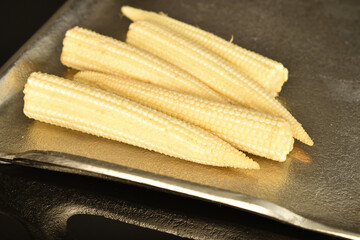 Ripe sweet ears of mini corn, close-up, isolated on black.