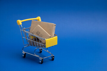 Yellow shopping cart or trolley and small , Product box, Package box , Isolated on blue background...