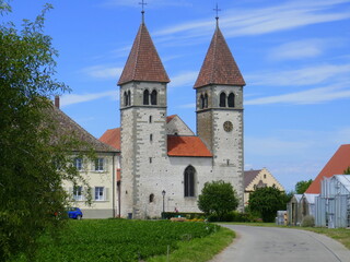 Fototapeta premium Kirche St. Peter und Paul auf der Insel Reichenau am Bodensee mit einer Radlerin im Vordergrund