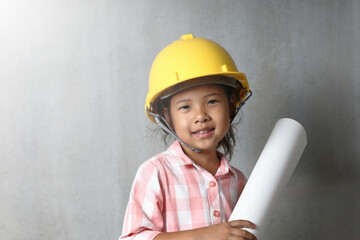 Portrait kid wearing hard hat yellow holding holding a blueprint. To learning and enhance development, little architect.