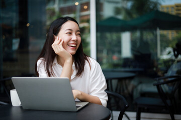 Asian woman working with computer laptop and drinking coffee in coffee shop cafe smile and happy face