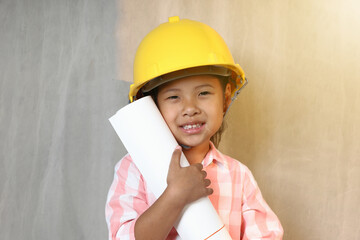 Portrait kid wearing hard hat yellow holding holding a blueprint. To learning and enhance development, little architect.
