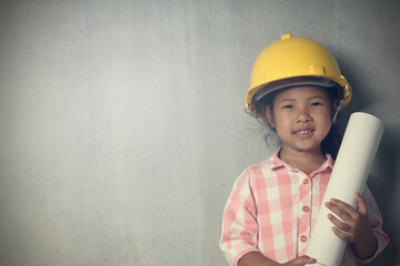 Little kid wearing hard hat yellow holding holding a blueprint. To learning and enhance...