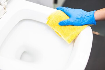 Cleaning the water closet with a scrub cloth.