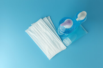 Alcohol gel bottles, hand sanitizer with white medical masks on blue background top view flat lay. This gel cleansers for antibacterial and virus for good sanitation hygiene.