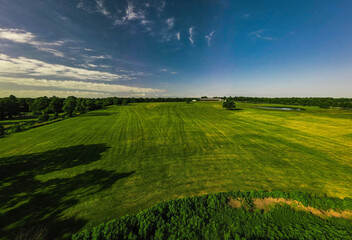 Fototapeta premium Aerial view of a mowed meadow in front of a farm building for storing hay