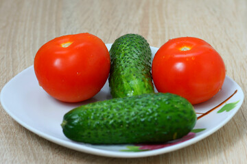 Two red tomatoes and two green cucumbers in a nice plate