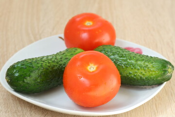 Two red tomatoes and two green cucumbers in a nice plate