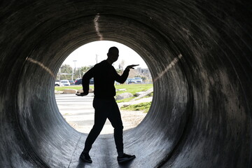 silhouette of a young man walking in the dark round tunnel