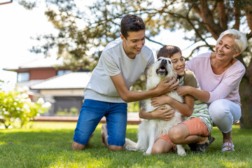 Mother and her sons playing with their dog in the garden

