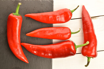 Red sweet organic peppers, close-up, on a wooden table.