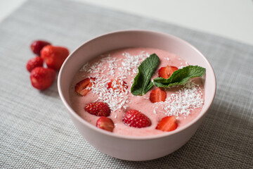Delicious smoothie bowl in pink bowl on a grey table