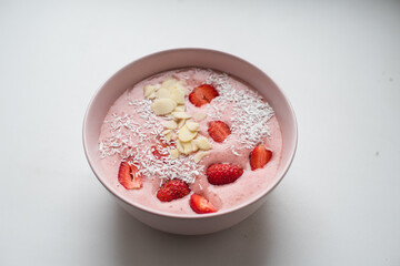 Fototapeta na wymiar Delicious smoothie bowl in pink bowl on a white table