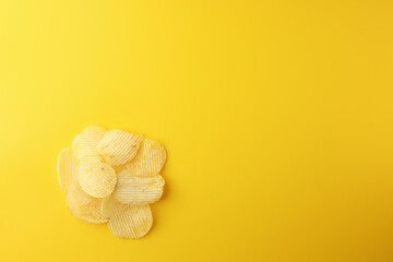Crispy potato chips snacks on yellow background. Image top view, flat lay, and copy space.