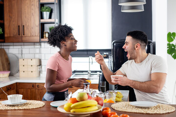 Multiethnic couple in the kitchen prepare smoothie with healthy tropical fruits