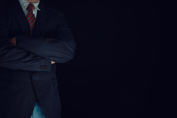 Businessman wearing a black suit, arms crossed. Concept, business, industrial, success on black background with copy space.