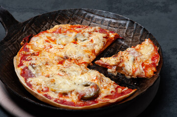 Fresh Pizza in an rustic iron Pan on a Slate Plate. Close up.