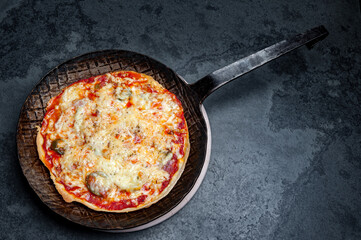 Fresh Pizza in an rustic iron Pan on a Slate Plate