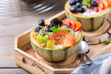 Fruit salad with yogurt in carved melon cantaloupe bowl