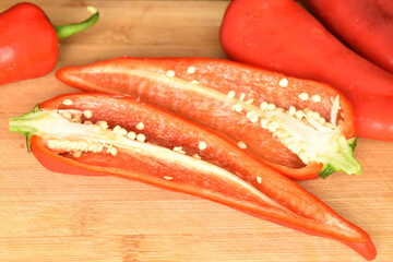 Red organic bell peppers, close-up, on a bamboo table.