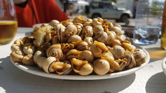 Eating small cooked snails. A Typical portuguese appetizer