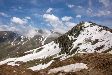 Fototapeta premium Snowy mountains that begin to melt and become green with spring and around