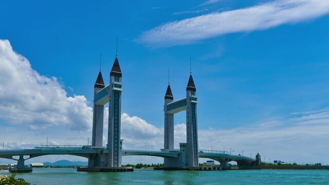 A timelapse of a bridge with rolling clouds and blue skies.