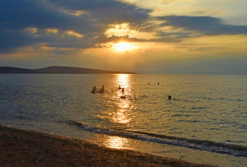 Silhouettes of people in the sea at sunset