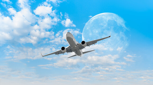 White passenger airplane in the clouds with full moon  - Travel by air transport "Elements of this image furnished by NASA"