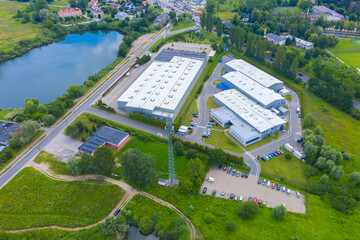 Aerial view of modern storage warehouse with solar panels on the roof. Logistics center in industrial city zone from drone view. Background texture concept.