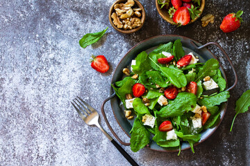 Healthy food concept, Diet salad plate. Summer salad with strawberries, fetacheese and walnut on a stone countertop. Top view flat lay background. Copy space.