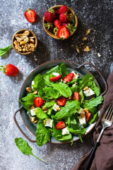 Healthy food concept, Diet salad plate. Summer salad with strawberries, fetacheese and walnut on a stone countertop. Top view flat lay background.