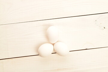 A few chicken eggs, close-up, on a white wooden table.