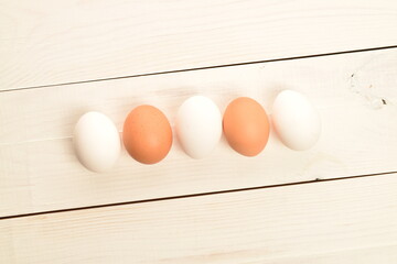 A few chicken eggs, close-up, on a white wooden table.