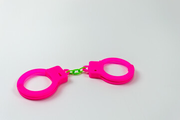 The toy handcuffs are pink on a white background.