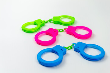 The toy handcuffs are available in green, pink and blue. On a white background.